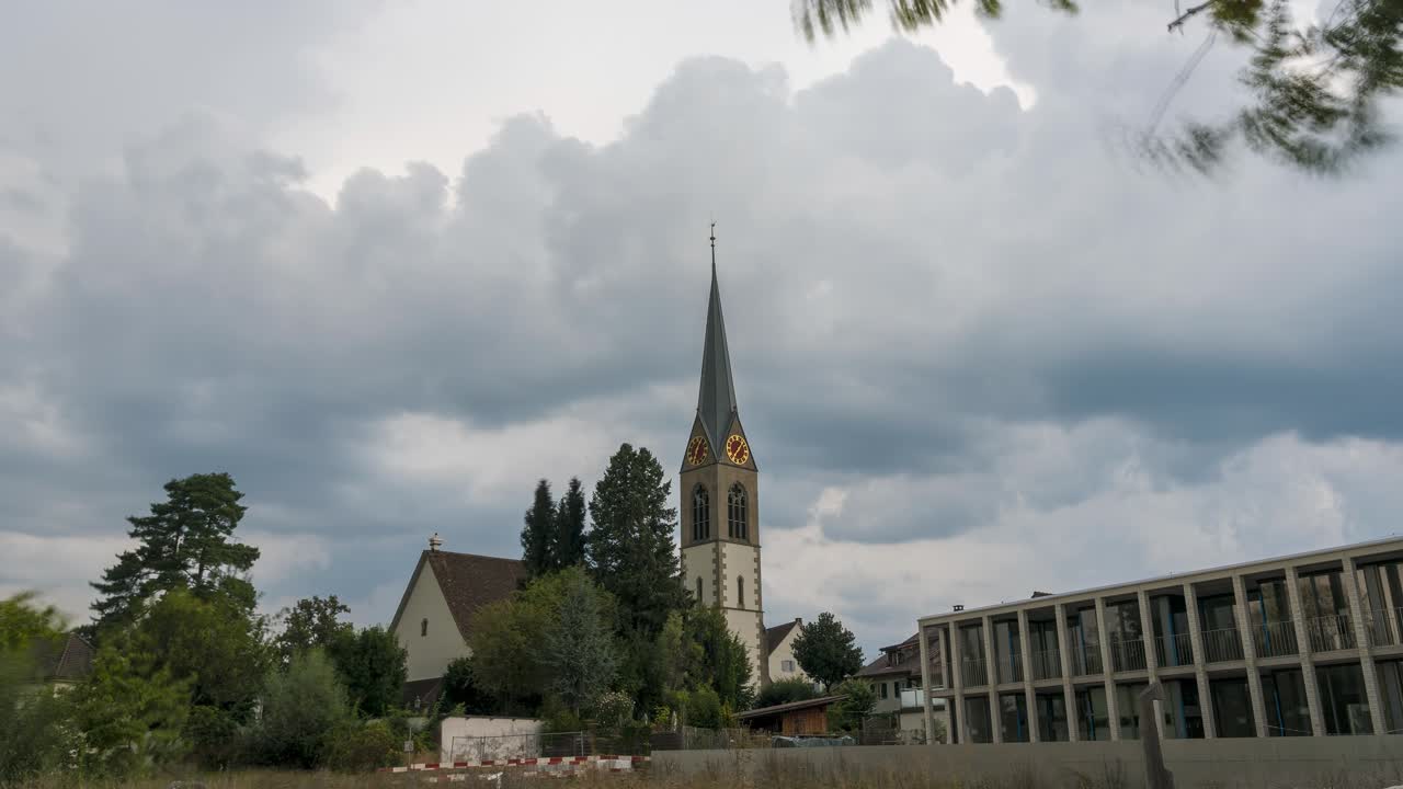 Thick clouds move over a church. The church clock rotates faster because it is filmed in fast motion. Timelapse