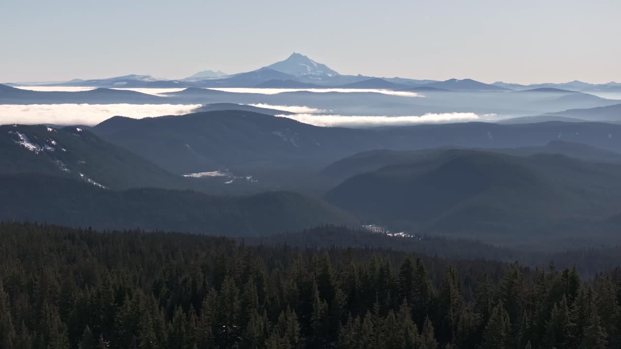 Ampia ripresa aerea con drone del vulcano a strati Monte Jefferson in lontananza, con fitte pinete e inversione nuvolosa, scattata con un DJI Mavic 3 Pro nella Foresta Nazionale di Mount Hood
