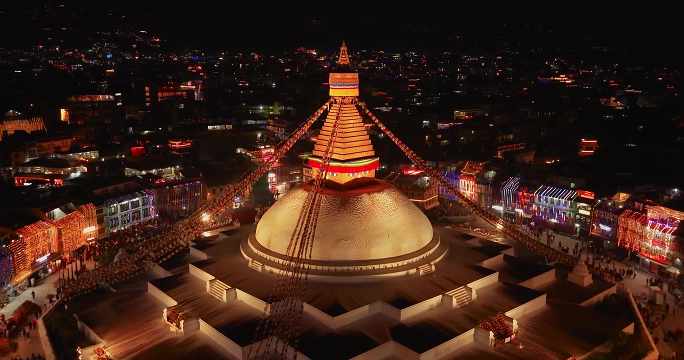 Kathmandu, Nepal, Drone scivola sopra lo Stupa di Boudhanath splendidamente illuminato e la città illuminata sullo sfondo durante la notte delle festività del Tihar