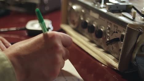 escuchando pruebas delictivas de una vieja grabadora y tomando notas en papel