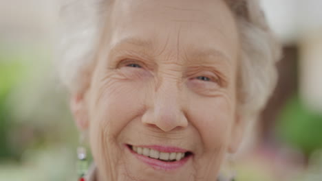 close up portrait of elderly caucasian woman laughing cheerful looking at camera enjoying happy retired lifestyle in sunny outdoors slow motion wrinkled skin