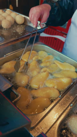 fried dough/pastries being cooked at a street food stall