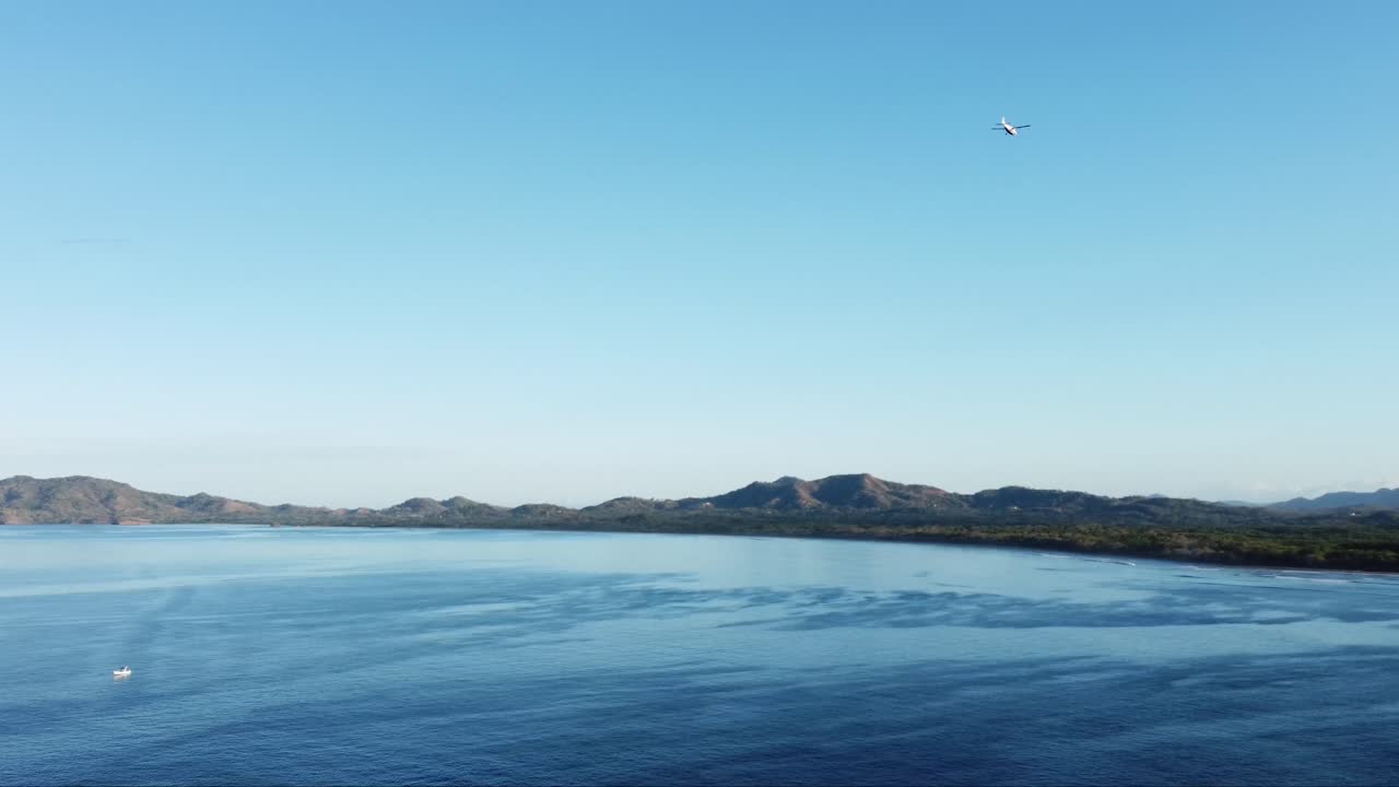 코스타리카의 젊고 재미있는 파티 마을 플라야 타마린도의 해안선 바로 옆에 있는 태평양 상공을 비행하는 비행기