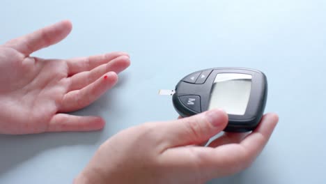 hands of caucasian woman checking blood sugar level using glucometer, slow motion