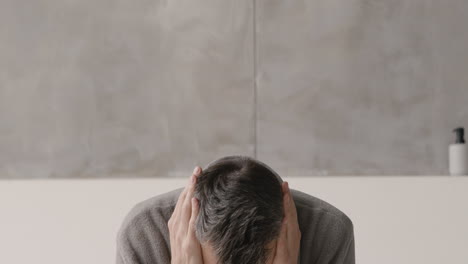 suffering middle aged man in pajamas and robe having headache at home