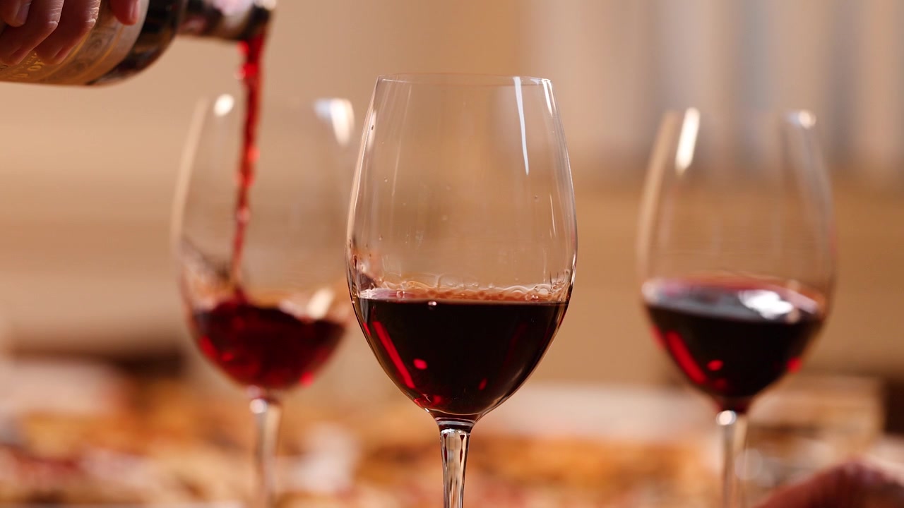 Primo piano di vino rosso versato in un bicchiere durante una cena di festa in un ristorante.