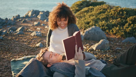 handsome man reading book at picnic for relaxed woman closeup. romantic couple