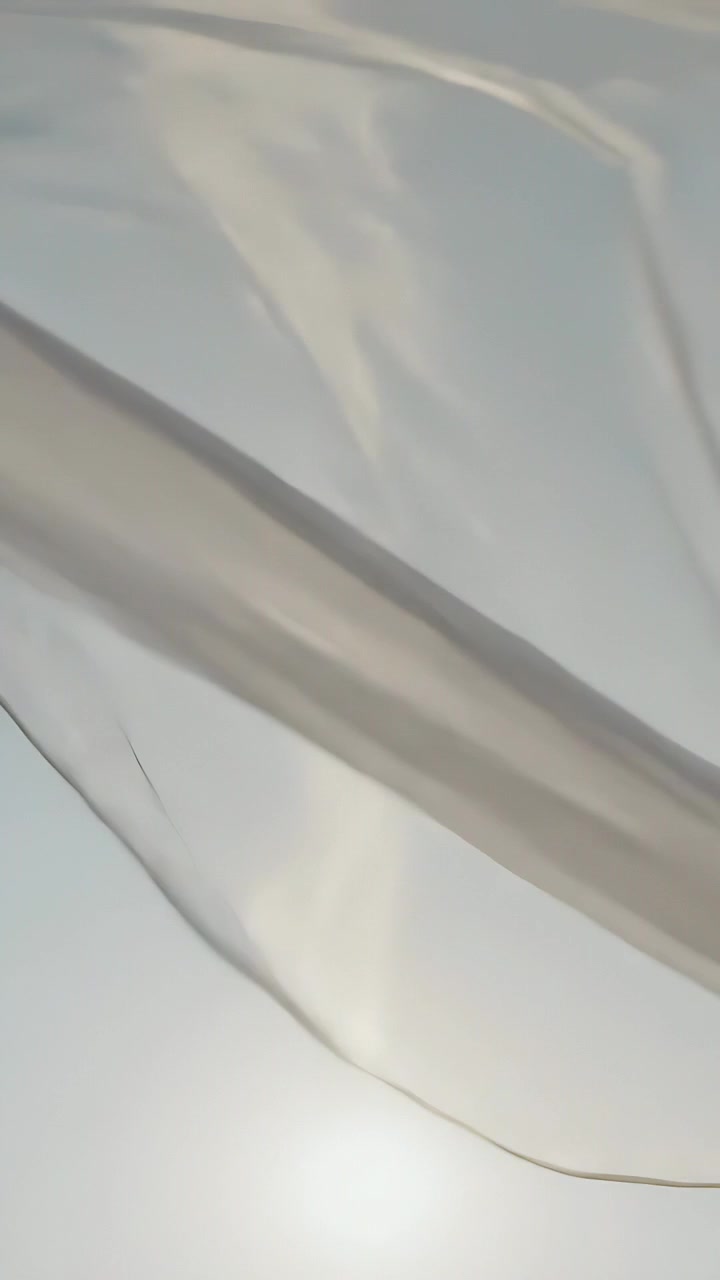 Video verticale: Brezza che muove una tenda trasparente che ondeggia nel cielo, rivelando e velando il sole vicino a un filo.