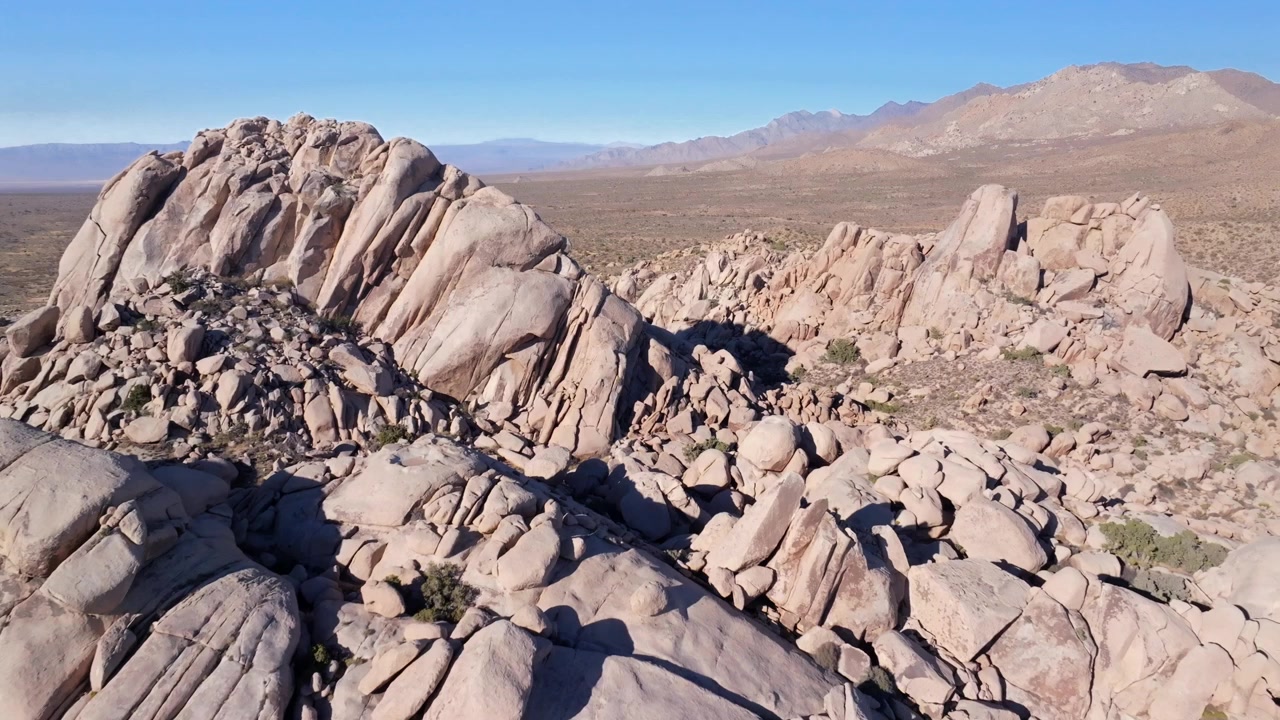 Formazione rocciosa collinare aspra, Dune di Kelso Pinto Basin, Parco Nazionale Joshua Tree California, drone aereo, Alberi di Yucca, Contea di San Fernando, deserto del Mojave e del Colorado, cielo blu, pomeriggio soleggiato, movimento in avanti