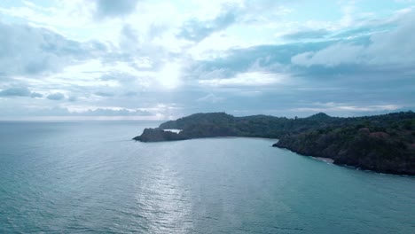 Rotating-around-island-with-ocean-in-view,-and-dark-big-cloudscape,-aerial