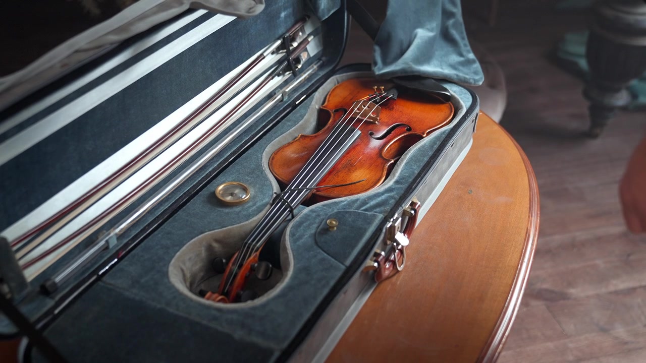 Professioneller Musiker öffnet Violinkoffer und entnimmt Instrument.