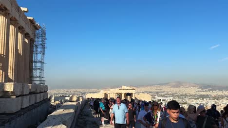 the acropolis parthenon buzzes with visitors on a bright, hot summer day.