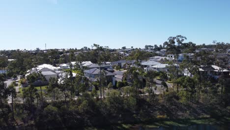 Drone-Ascendiendo-Sobre-Un-Lago-Artificial-Para-Revelar-Un-Suburbio-De-Lujo-Con-Grandes-Casas-Familiares-En-Australia