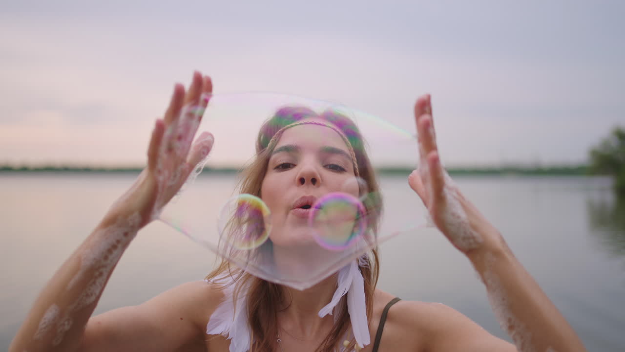 una joven artista muestra trucos de magia usando burbujas de jabón. cree burbujas de jabón en sus manos e inflelas ubicación espectáculo de circo teatral al atardecer
