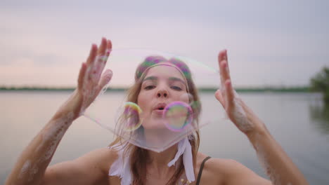 a young girl artist shows magic tricks using soap bubbles. create soap bubbles in your hands and inflate them location theatrical circus show at sunset