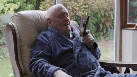 an elderly man relaxing at home using a phone