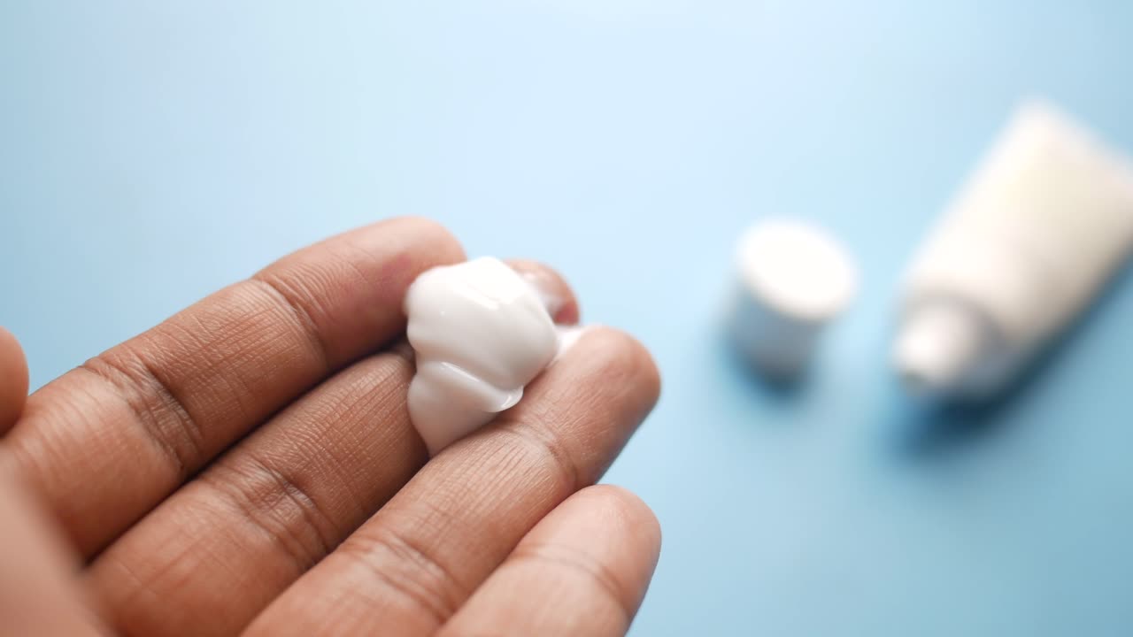 mano sosteniendo una mancha de crema facial blanca