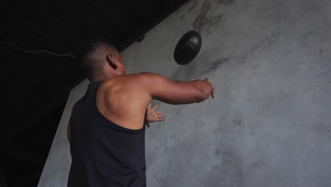 african american man exercising with medicine ball in an empty urban building