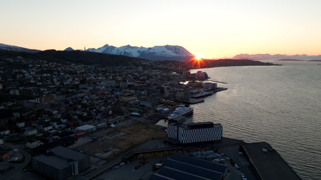 Drone kredser langsomt om Harstad langs fjorden ved gyldentid, luftfoto