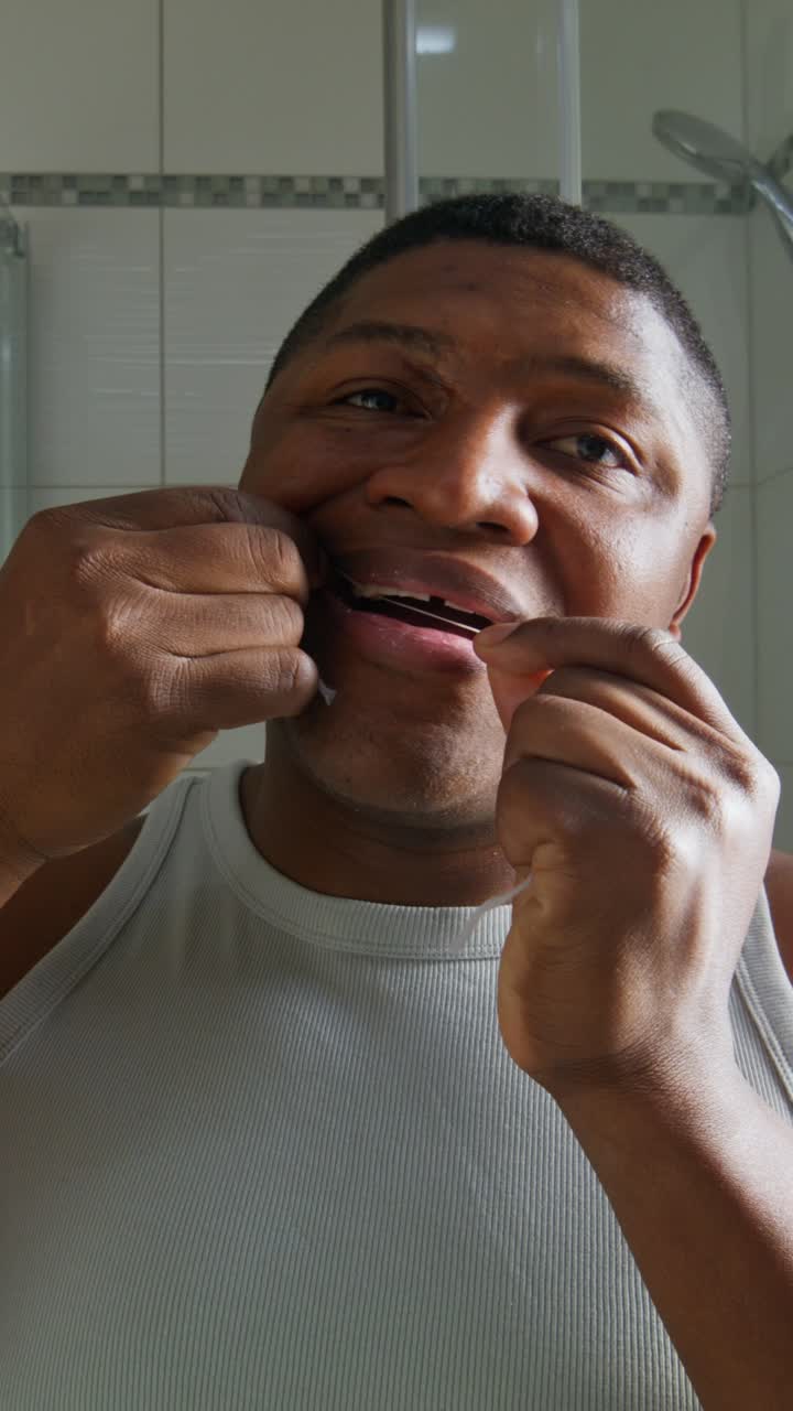 Man Flossing Teeth in Bathroom