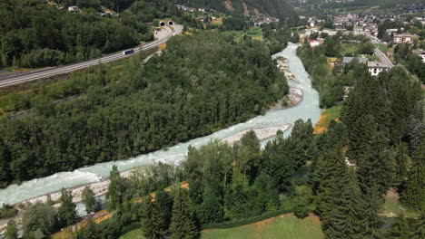 Bosque-Denso-Río-De-Montaña-Cerca-De-La-Autopista-Con-Fondo-De-Pueblo-En-Morgex-Valle-D&#39;aosta,-Italia