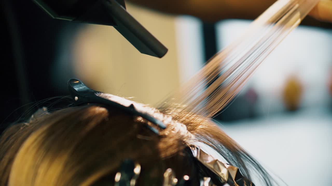 Hairstylist using blow dryer to apply heat. Drying hair. Hair colouring with foil.