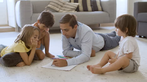 sibling kids and dad sitting and lying on warm floor