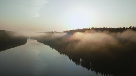 beautiful foggy lake aerial shot through clouds at sunrise