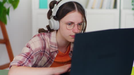 adolescente concentrada mientras hacía la tarea en la computadora portátil y tomaba clases en línea