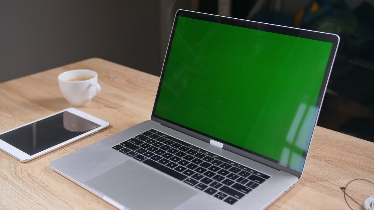 Laptop, tablet, and coffee cup on a wooden table