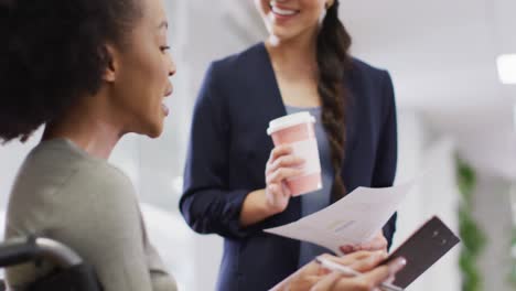 Diverse-and-disabled-business-people-holding-documents-and-talking-in-office,-slow-motion