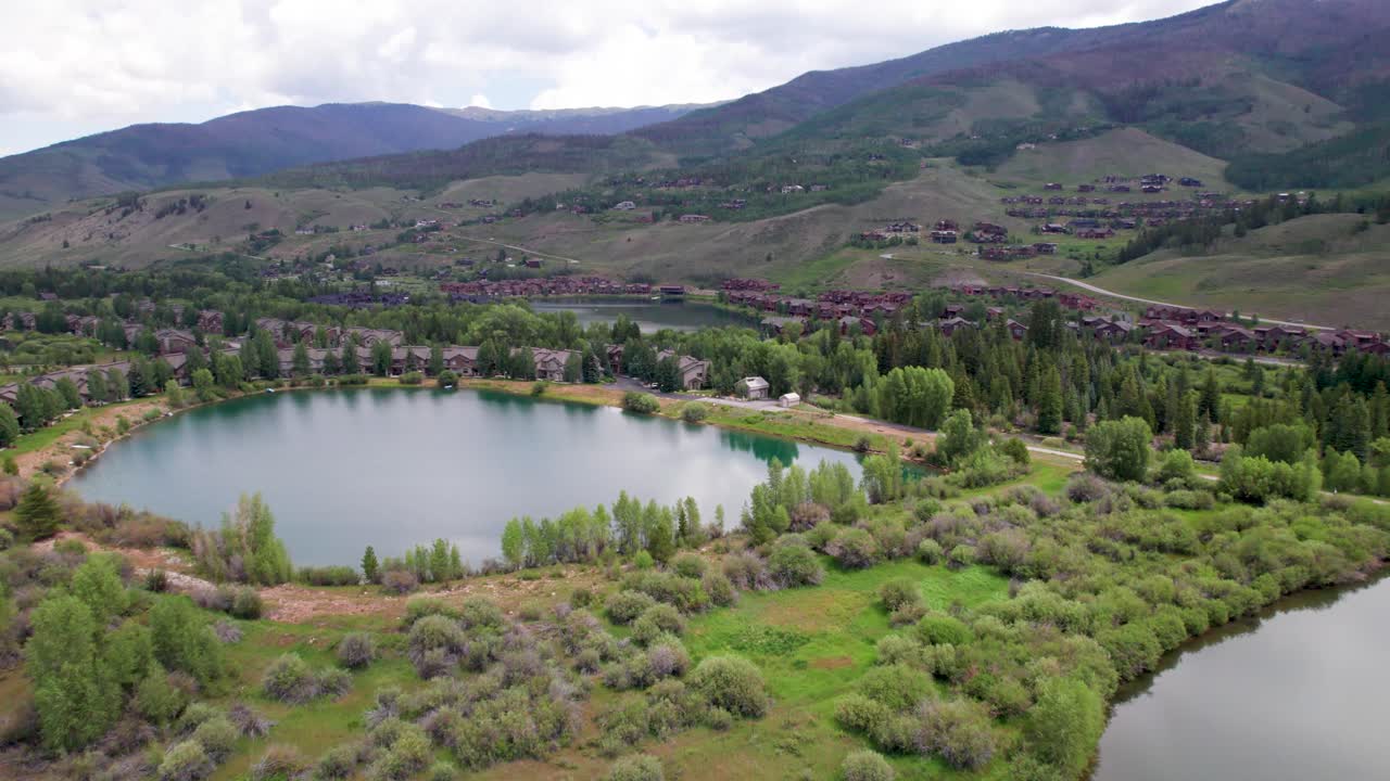 Aerial video of ponds near Silverthorne, Colorado. Camera flies over a pond with houses in the background.