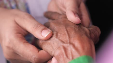 persona joven sosteniendo suavemente la mano de una persona mayor