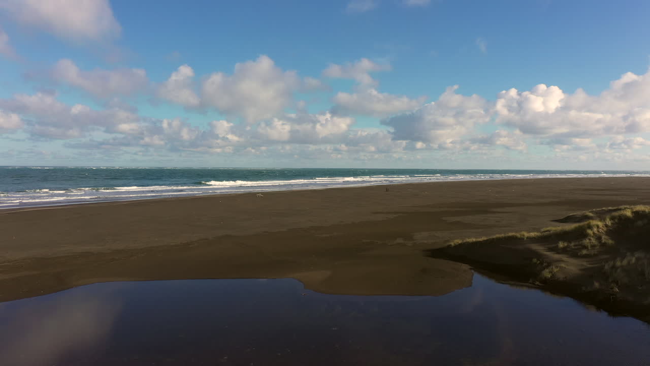 volando sobre la playa de arena negra whatipu hacia olas masivas, reserva huia