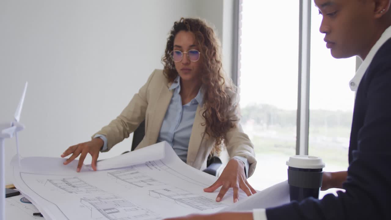 arquitectas biraciales hablando y comprobando planes de arquitectos en oficinas modernas