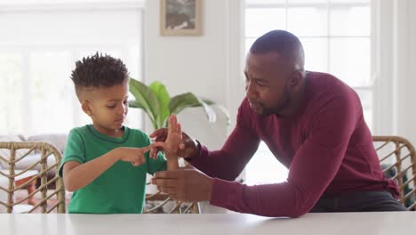 Feliz-Hombre-Afroamericano-Y-Su-Hijo-Sentados-A-La-Mesa-Y-Hablando-Lenguaje-De-Señas