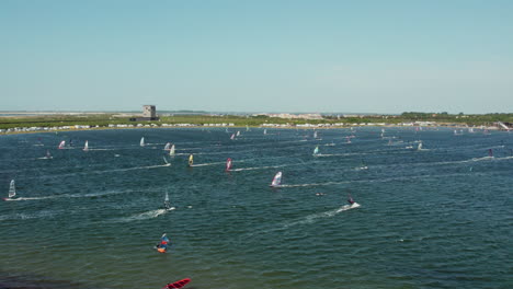 multiple windsurfing people on blue water in brouwersdam beach, netherlands - aerial shot