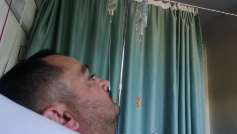 un paciente varón en el hospital observa su goteo salino