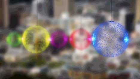 Multiple-colorful-baubles-decorations-against-aerial-view-of-night-cityscape