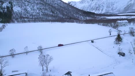 black car driving on the road surrounded in snow during winter in andoya island, norway