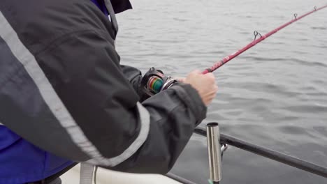 hombre en barco rodando rápidamente la caña de pescar en el río en noruega