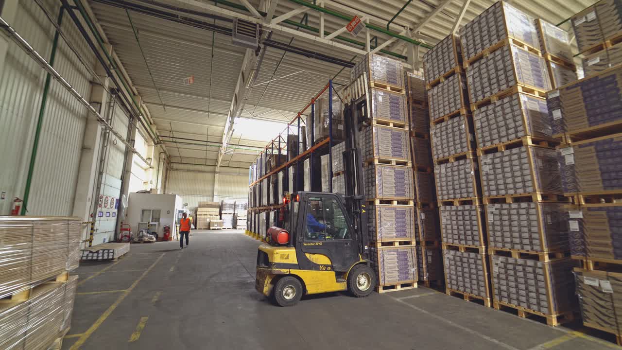 Forklift truck pulled up to a pile of wooden pallets. Factory for the production of parquet board