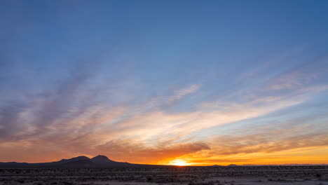 colorido amanecer azul y dorado en el desierto de mojave con las montañas en silueta - lapso de tiempo estático de gran angular