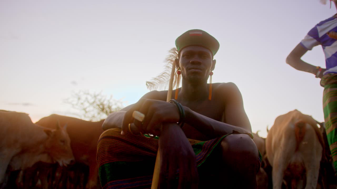Traditional African Warrior Sitting Down Next To His Cows In Karamoja, Uganda - Close Up