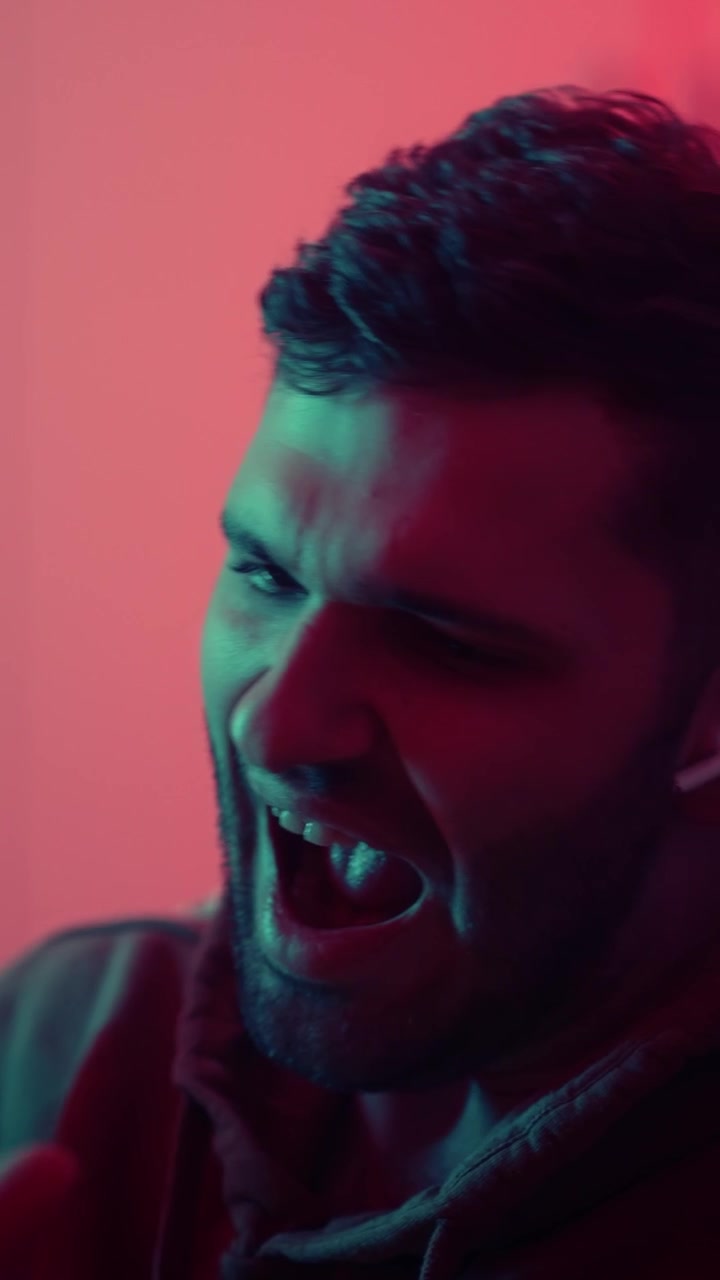 Giovane uomo che esprime un'emozione intensa con un'illuminazione al neon drammatica