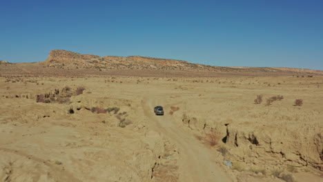 aerial as car drives through desert ravine on rugged dirt road in new mexico