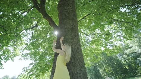 woman in yellow dress dancing by tree in summer park