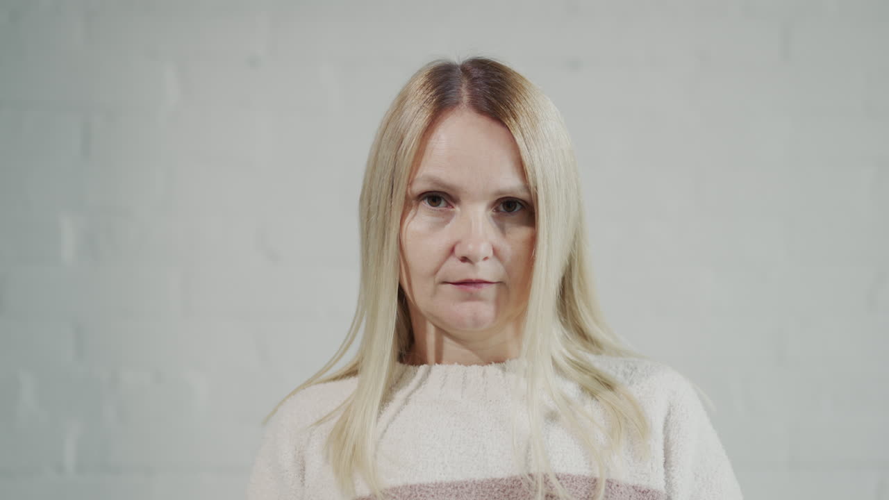 Woman critically examines herself in the mirror, looks at the camera