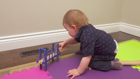 baby boy putting a toy train track together