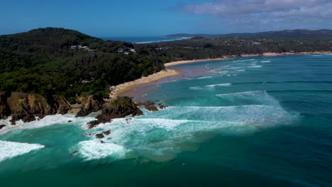 wide rotating drone shot of surfers in the ocean at wategos beach in byron bay, australia